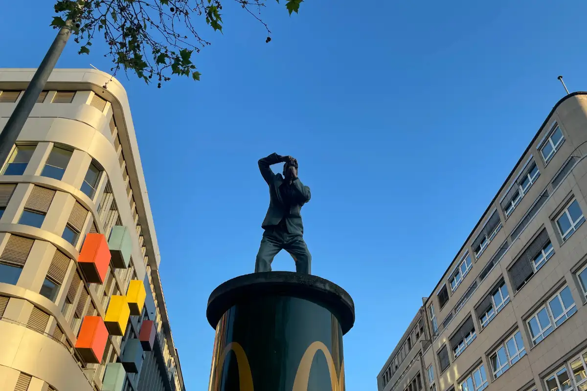 Lebensgroße Figur eines Fotografen hoch oben auf einer Litfaßsäule