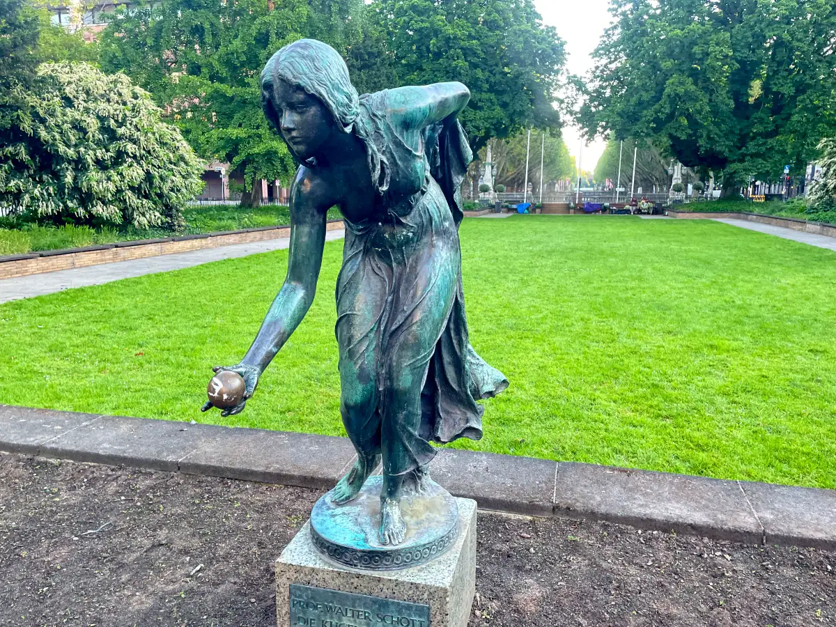 Skulptur Die Kugelspielerin vor einer Rasenfläche