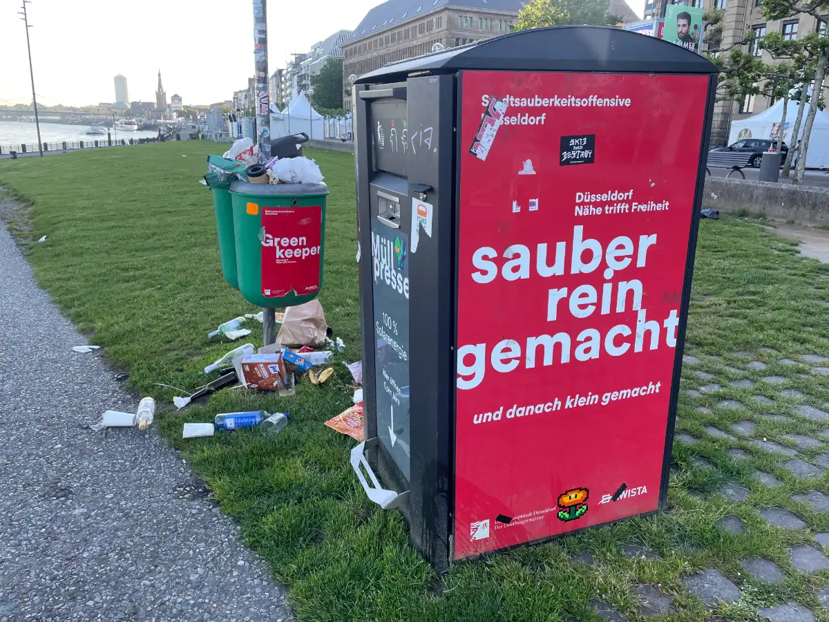 Müllpresse und völlig überfüllte Mülleimer an der Rheinpromenade