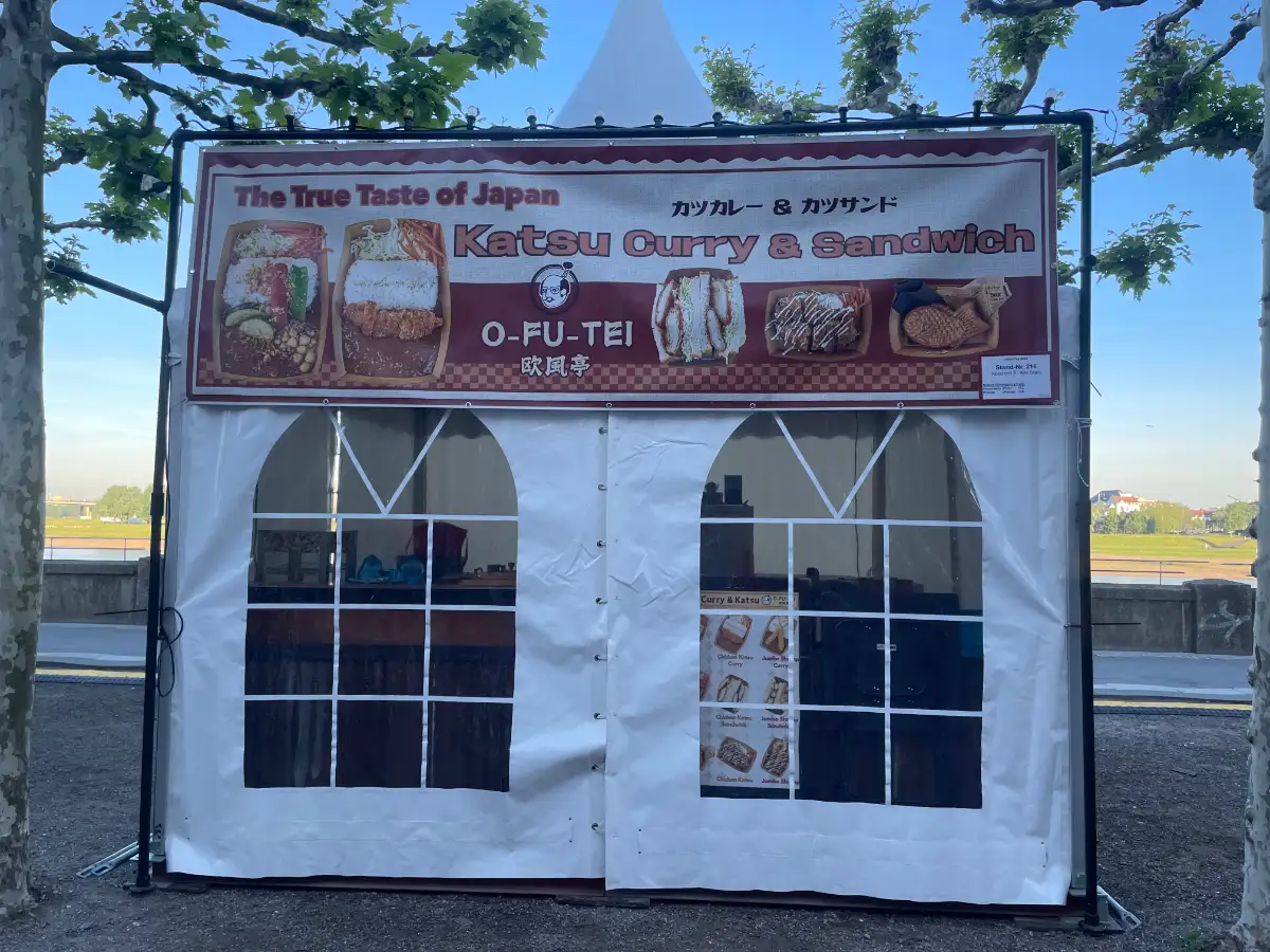 Zelt mit Banner, das für „Katsu Curry & Sandwich“ wirbt