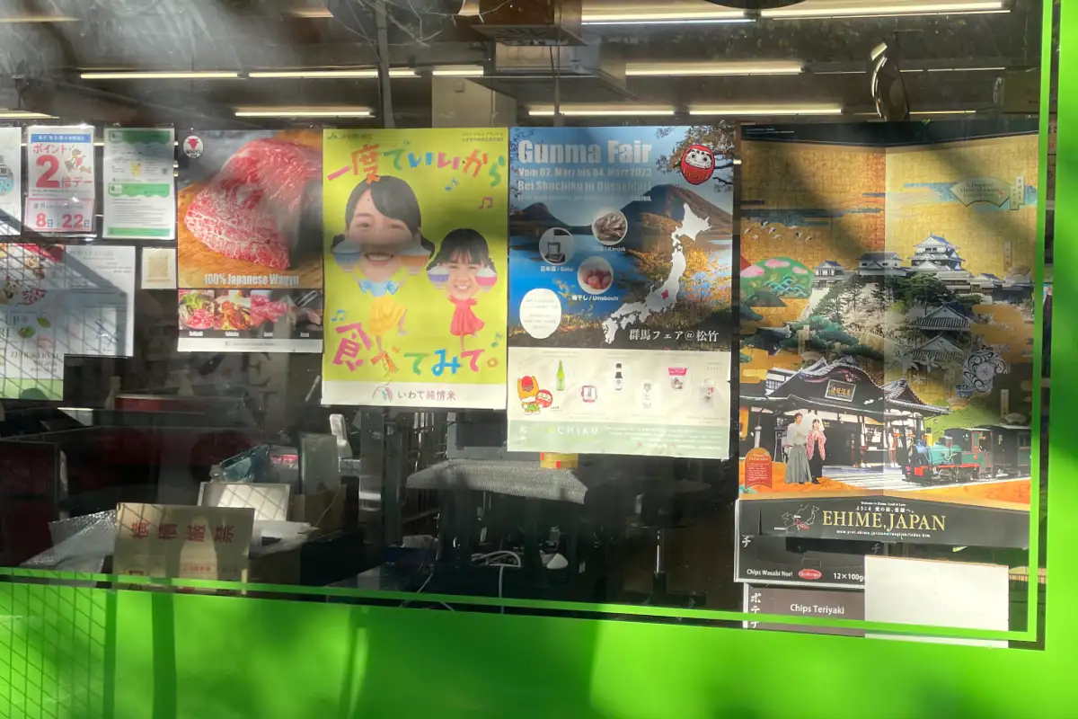 Schaufenster eines japanischen Supermarkts mit japanischen Plakaten