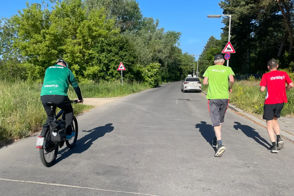 Läufer mit Fahrradbegleiter auf einer einsamen Straße