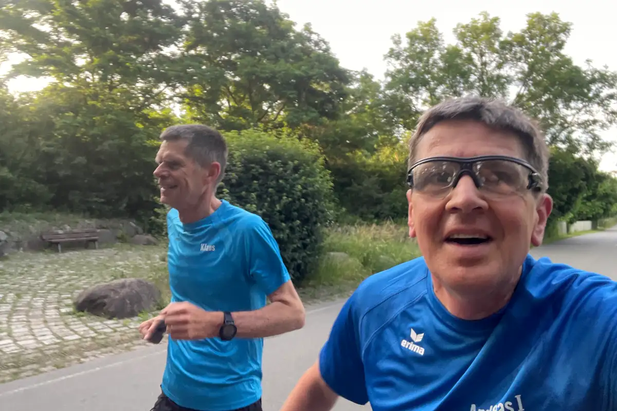 2 Läufer in blauen Shirts laufen schnell auf einer einsamen Straße