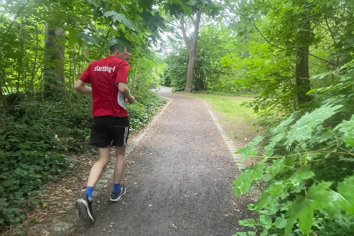 Läufer im roten startblog-f-Shirt auf einem schmalen Parkweg