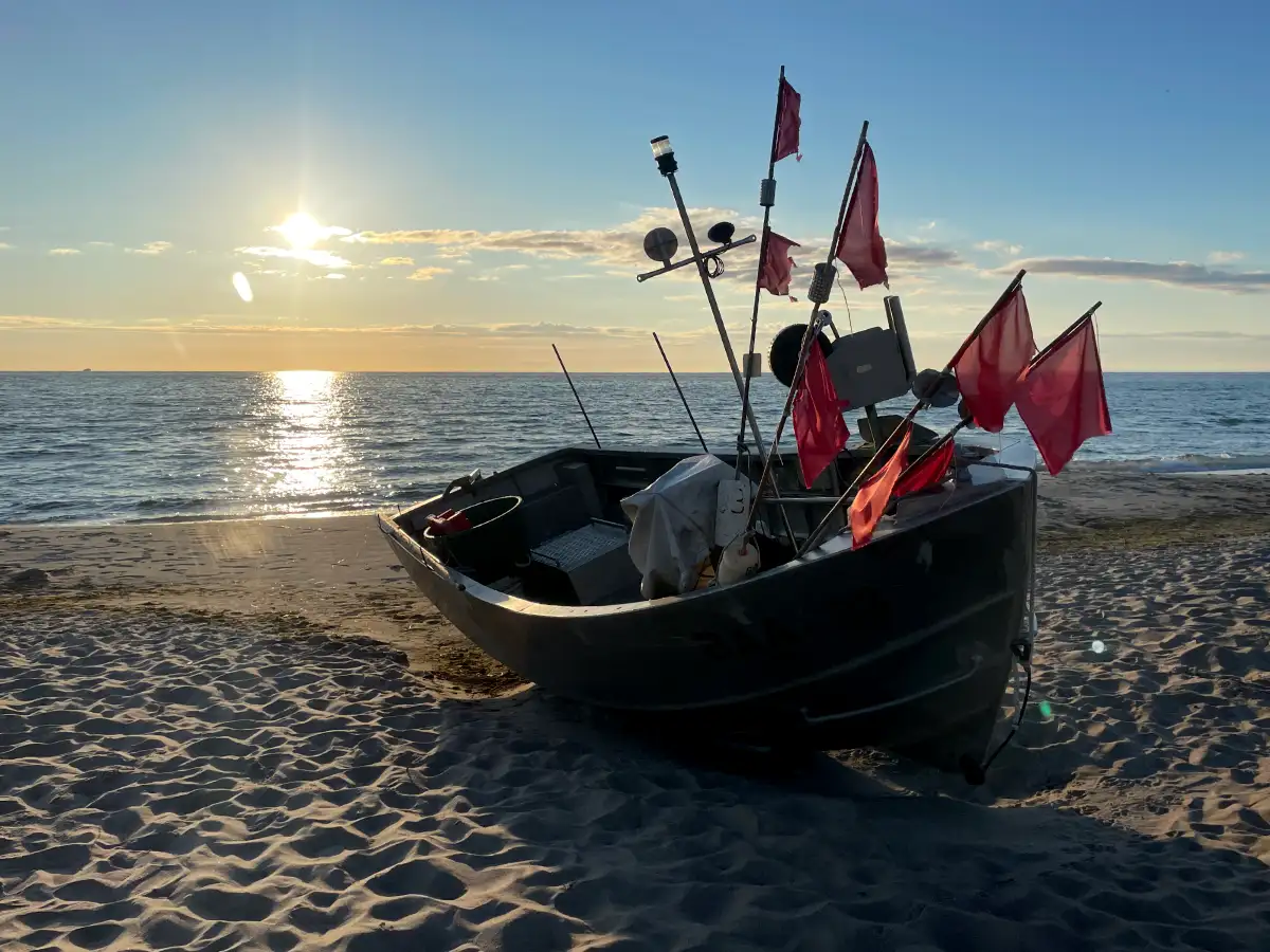Boot mit roten Fahnen am Strand
