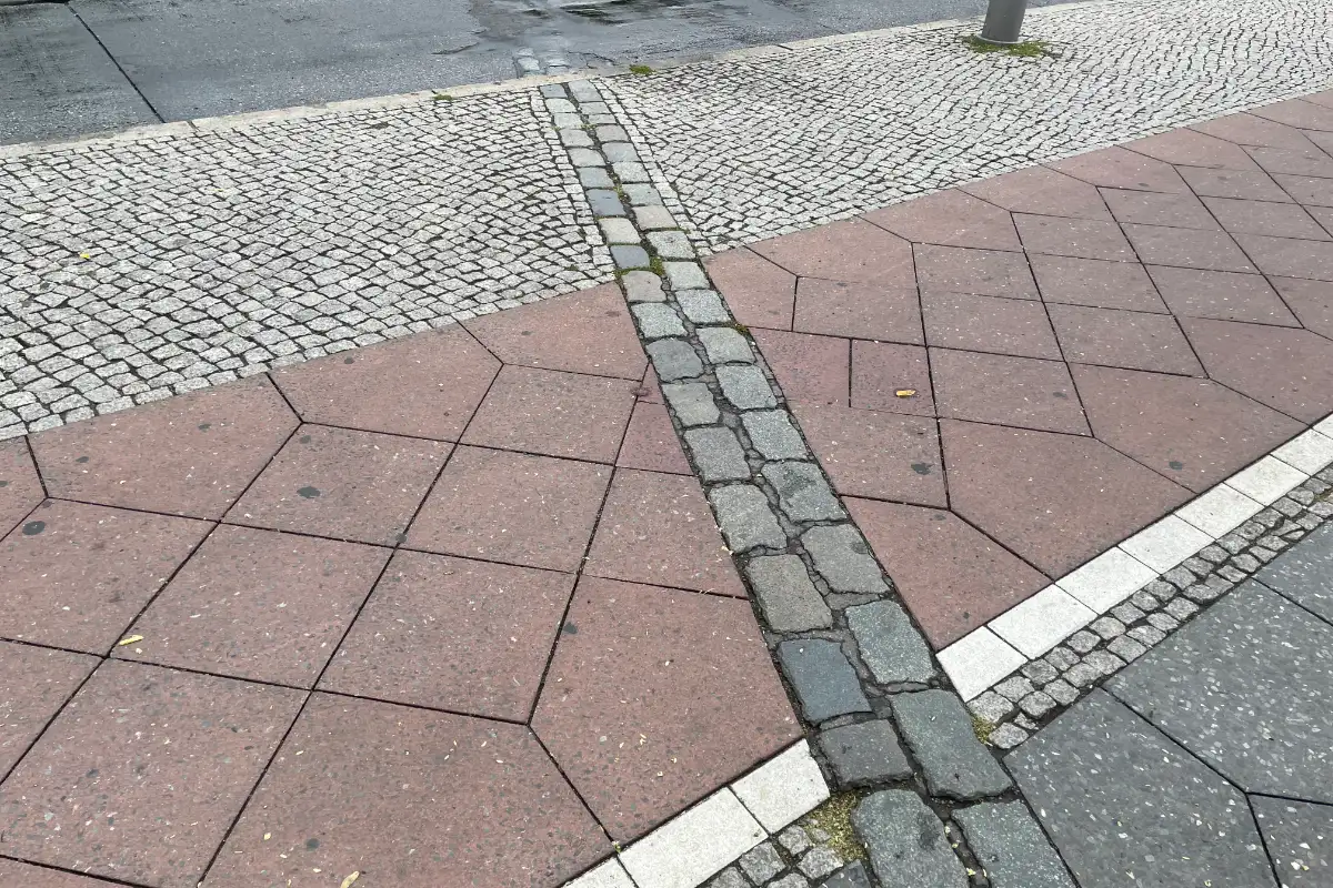 Markierter Mauerverlauf quer über Fußweg, Radweg und Straße