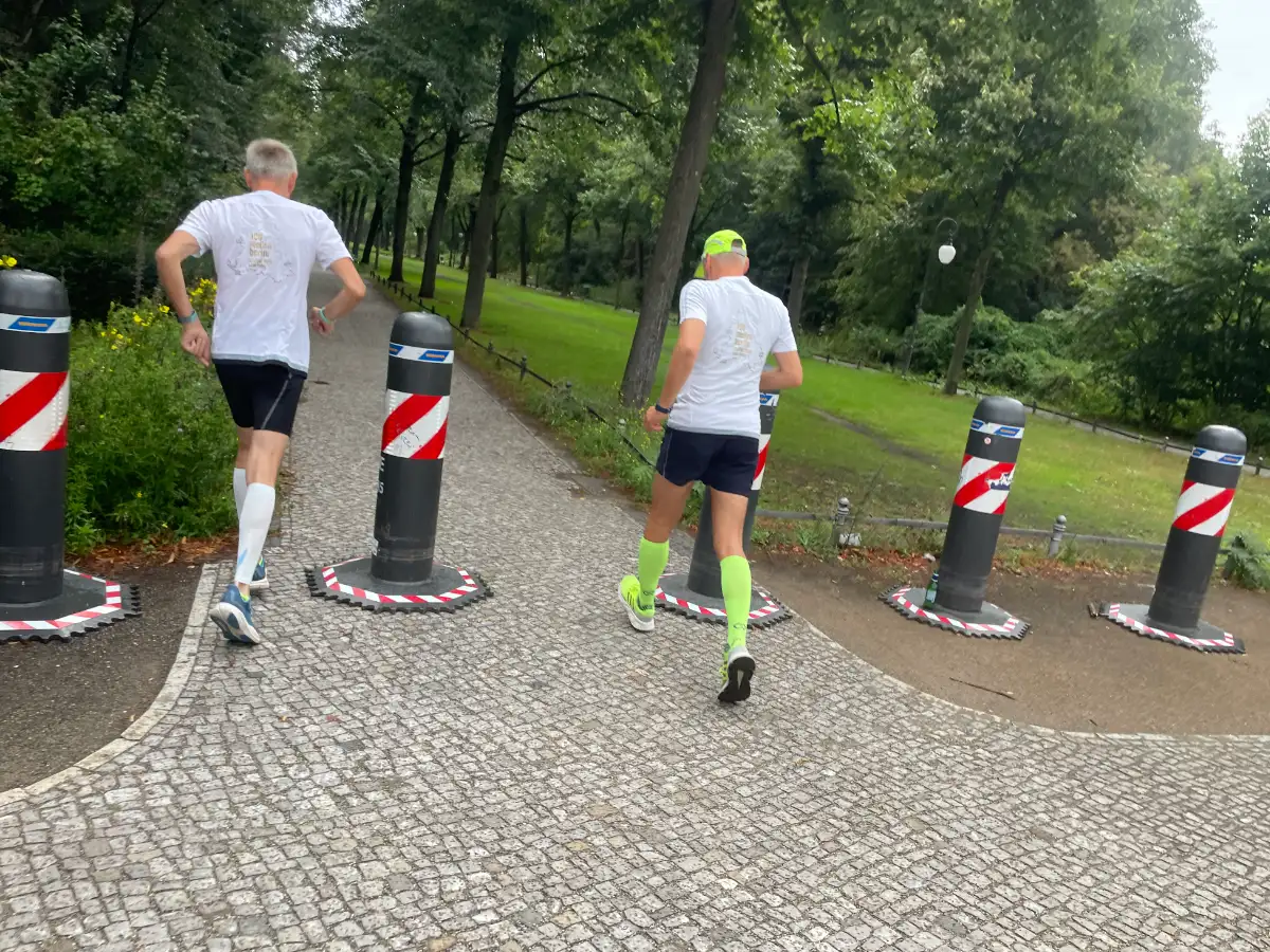 Läufer laufen in den Tiergarten, zwischen dicken mobilen Pollern hindurch
