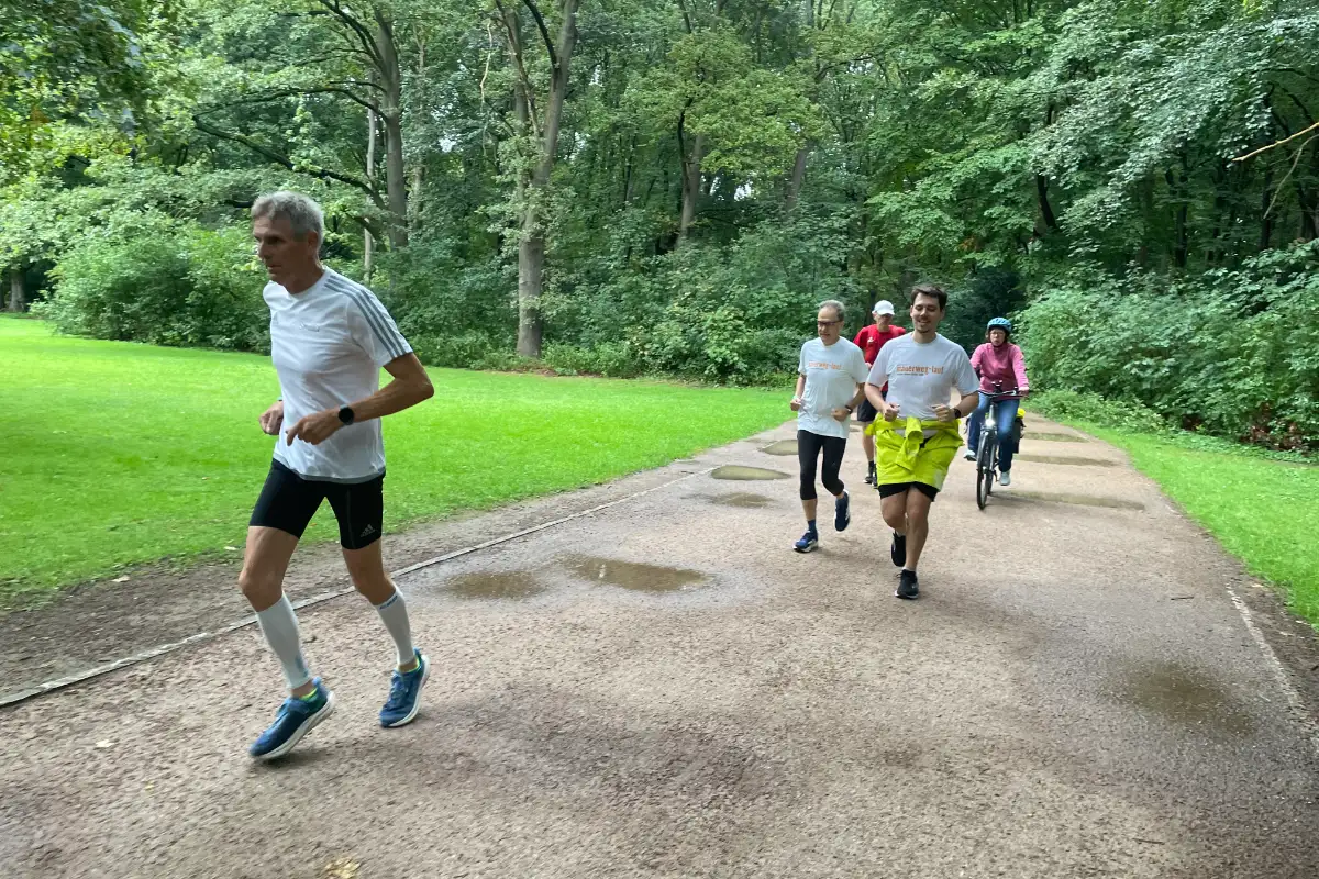 Laufgruppe mit Radbegleitung auf Parkweg im Tiergarten