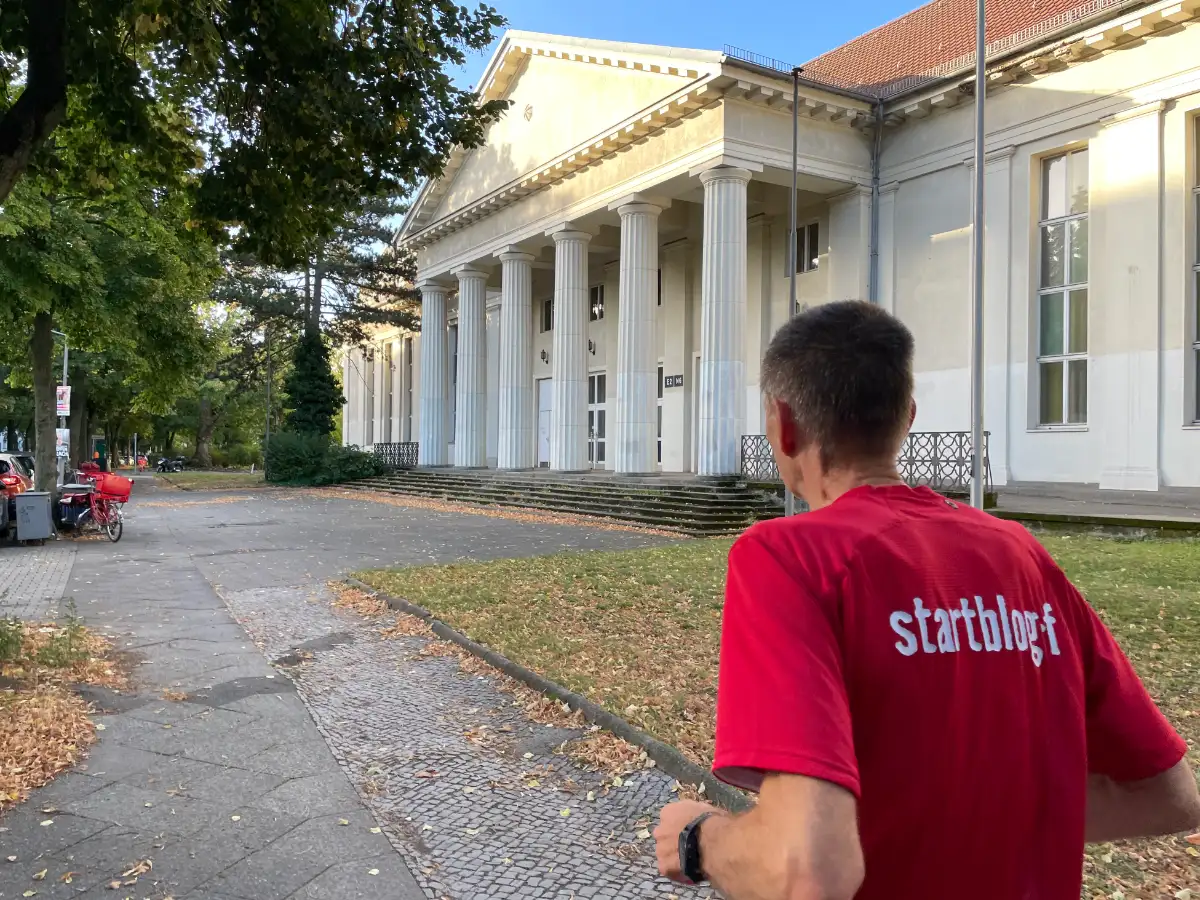 Läufer und großes weißes Gebäude mit Säulenportal