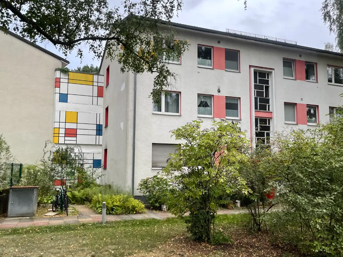 3-stöckiges Mietshaus aus den vielleicht 50er-Jahren, daneben an Wand Farbdekoration im Stil von Mondrian