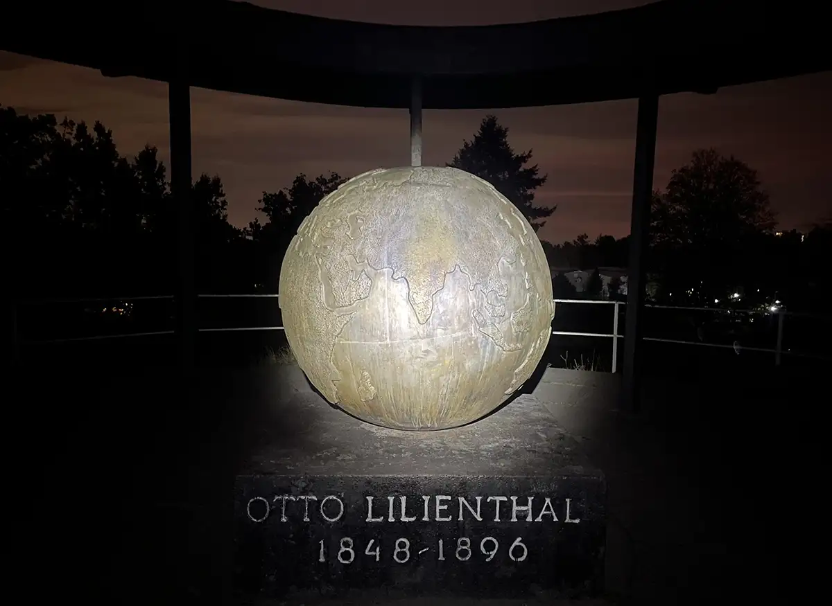 Weltkugel des Lilienthal-Denkmals im Scheinwerfer-Licht der Stirnlampe, dahinter erste Morgendämmerung